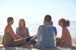 © Trevor Adeline/Caia Image - Happy friends talking in circle on sunny beach during yoga retreat