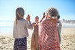 © Trevor Adeline/Caia Image - Women friends hands clasped in circle on sunny beach during yoga retreat