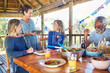 © Trevor Adeline/Caia Image - Friends enjoying healthy meal in hut during yoga retreat