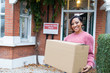© Robert Daly/Caia Image - Portrait smiling, confident woman moving into new house, holding cardboard box outside house