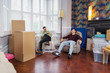 © Robert Daly/Caia Image - Men taking a break from moving house, relaxing and laughing in armchairs