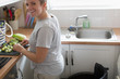 © Martin Barraud/Caia Image - Portrait smiling young woman wheelchair cutting vegetables in apartment kitchen