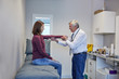 © Trevor Adeline/Caia Image - Male doctor examining arm of female patient in clinic examination room
