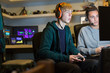 © Tom Merton/Caia Image - Teenage boys with headphones playing video game at computer in dark room