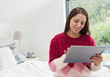 © Robert Daly/Caia Image - Woman using digital tablet in bedroom