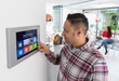 © Chris Ryan/Caia Image - Man setting touch screen smart home alarm
