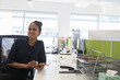 © Martin Barraud/Caia Image - Smiling businesswoman using smart phone in open plan office