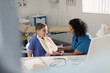 © Tom Merton/Caia Image - Female doctor checking arm sling of boy patient in doctors office