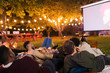 © Paul Bradbury/Caia Image - Friends relaxing, watching movie on projection screen in backyard