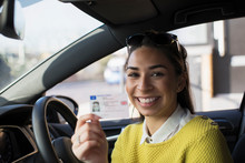 Portrait Happy Young Woman Holding New Drivers License In Car
