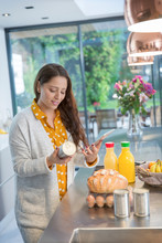 Woman With Digital Tablet Checking Food Labels In Kitchen