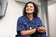 © Sam Edwards/Caia Image - Portrait smiling, happy female doctor using smart phone