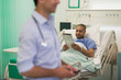 © Tom Merton/Caia Image - Male patient reading newspaper, resting in hospital room