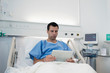 © Sam Edwards/Caia Image - Male patient using digital tablet, resting in hospital bed