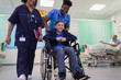 © Tom Merton/Caia Image - Doctor and nurse pushing boy patient in wheelchair in hospital ward