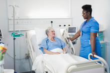 Female Nurse Talking With Senior Patient In In Hospital Room