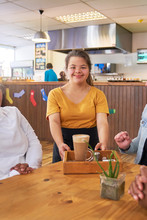Portrait Happy Young Female Server With Down Syndrome Working In Cafe