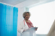© Sam Edwards/Caia Image - Senior female doctor with digital tablet making rounds in hospital room