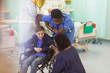 © Tom Merton/Caia Image - Doctor and nurse talking with boy patient in wheelchair in hospital ward