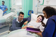 © Tom Merton/Caia Image - Doctor with digital tablet making rounds, talking with couple in hospital ward