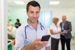 © Tom Merton/Caia Image - Portrait confident male doctor using smart phone in hospital ward