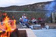 © Trevor Adeline/Caia Image - Senior friends relaxing with red wine on hotel patio with fire pit