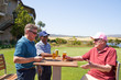© Trevor Adeline/Caia Image - Happy mature male golfers drinking beer at sunny golf course clubhouse