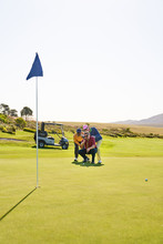 Male Golfers Planning Putt Shot On Sunny Golf Course Putting Green