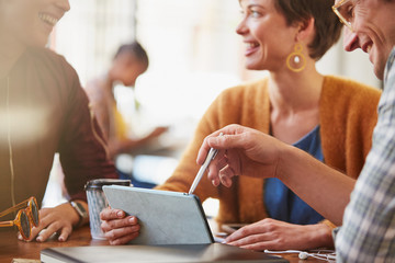 Smiling business people meeting using digital tablet in cafe