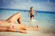 © Paul Bradbury/Caia Image - Son running toward mother sunbathing on sunny tropical beach