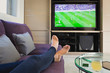 © Tom Merton/Caia Image - Personal perspective woman with bare feet up watching soccer game on TV in living room