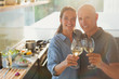 © Tom Merton/Caia Image - Portrait happy mature couple toasting white wine glasses, cooking in kitchen