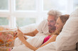 © Justin Pumfrey/Caia Image - Couple relaxing laying in bed using digital tablet