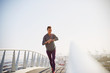 © Ryan Lees/Caia Image - Smiling female runner checking smart watch fitness tracker on sunny urban footbridge