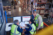 © Ryan Lees/Caia Image - Managers at laptop and computers discussing paperwork in distribution warehouse