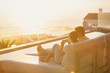 © Tom Merton/Caia Image - Silhouette couple using cell phone on chaise lounge with sunset ocean view