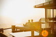 © Tom Merton/Caia Image - Silhouette couple relaxing on chaise lounge enjoying sunset ocean view