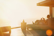 © Tom Merton/Caia Image - Silhouette woman using cell phone on chaise lounge on luxury balcony with sunset ocean view