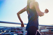 © Ryan Lees/Caia Image - Female runner running on sunny urban footbridge