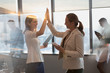 © Tom Merton/Caia Image - Businesswomen with digital tablets high-fiving in conference room