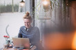 © Sam Edwards/Caia Image - Smiling young woman using laptop in cafe window