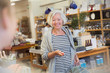 © Sam Edwards/Caia Image - Smiling mature female shopper with basket nearing checkout counter