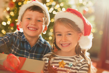 Portrait Smiling, Enthusiastic Brother And Sister Wearing Santa Hats Holding Christmas Gift