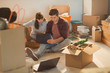© Justin Pumfrey/Caia Image - Young couple using laptop surrounded by moving boxes