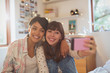 © Justin Pumfrey/Caia Image - Enthusiastic young women friends taking selfie with camera phone