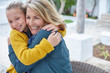 © Ryan Lees/Caia Image - Enthusiastic grandmother and granddaughter hugging on patio