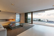 © Martin Barraud/Caia Image - Modern, minimalist luxury living room with gas fireplace and patio doors open to ocean view and patio