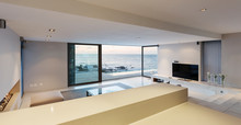 Modern, minimalist luxury living room with patio doors open to ocean view