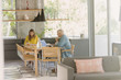 © Tom Merton/Caia Image - Mature couple working at laptop and eating at dining table