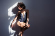 © Sam Edwards/Caia Image - Sensual young female dancer stretching leg in sunlight at wall